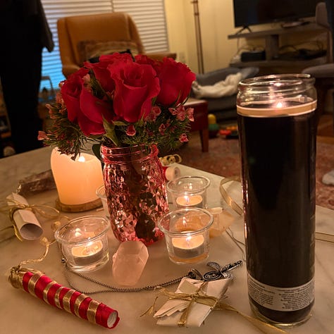 Hot pink roses, scrolls with red and gold ribbon, and crystals for travel ritual