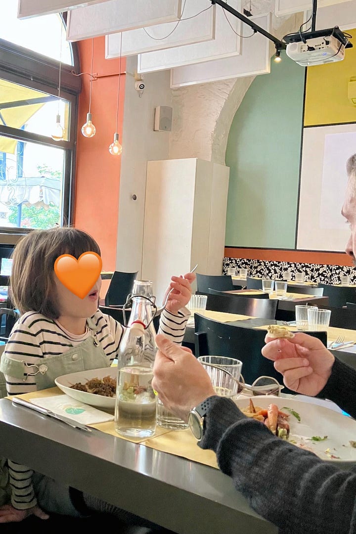 Collage di quattro scatti. Una bambina, Elena, pranza al ristorante con il papà. Un papà, con lo zaino della figlia in spalla, la accompagna all’ingresso della scuola. Tre bambini di spalle camminano verso l’ingresso della scuola con la mamma. Un altro papà solleva la sua bambina, piccola piccola, davanti alla vetrina di un locale. È un momento di immensa tenerezza.