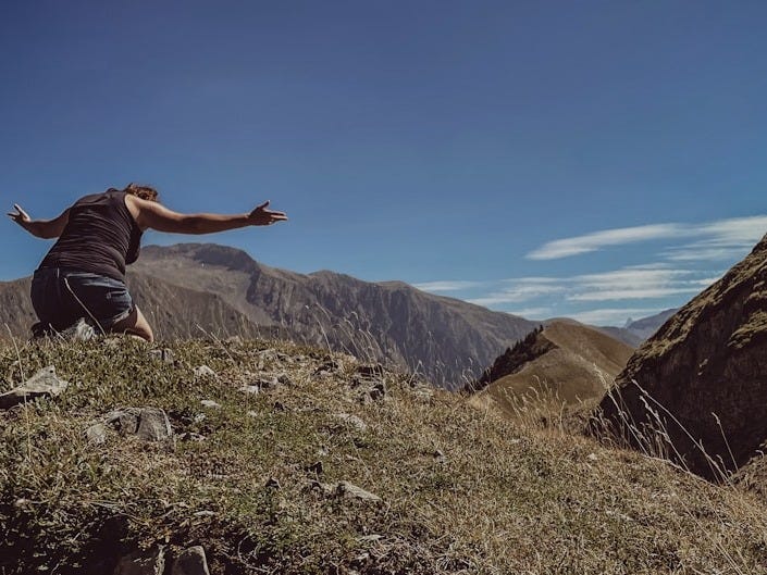 a man standing on top of a lush green hillside