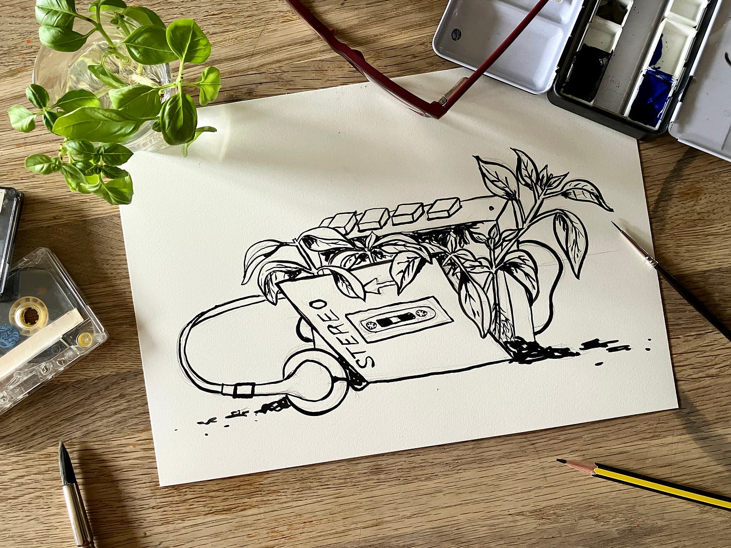 painting of cassette player with spring seedlings emerging from it sits atop a table surrounded by tapes, seedlings and art materials