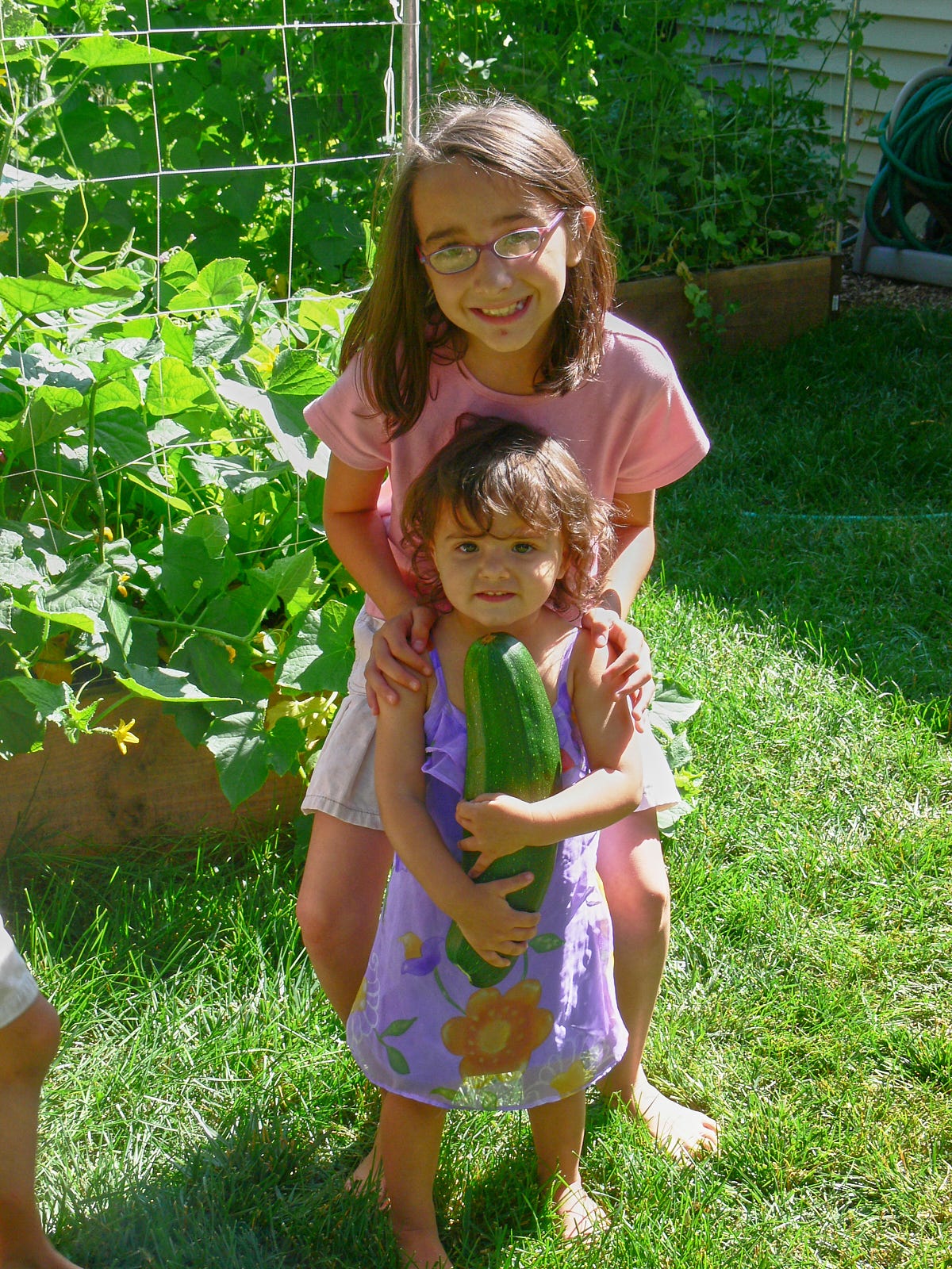 two girls holding a giant zucchini