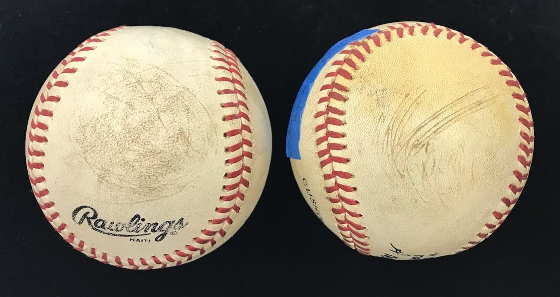Two marked-up baseballs, smudged and scratched.