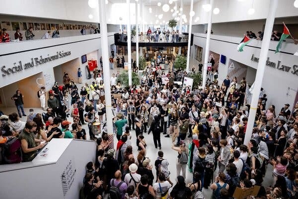 A crowd of people in a room with white pillars and walls.