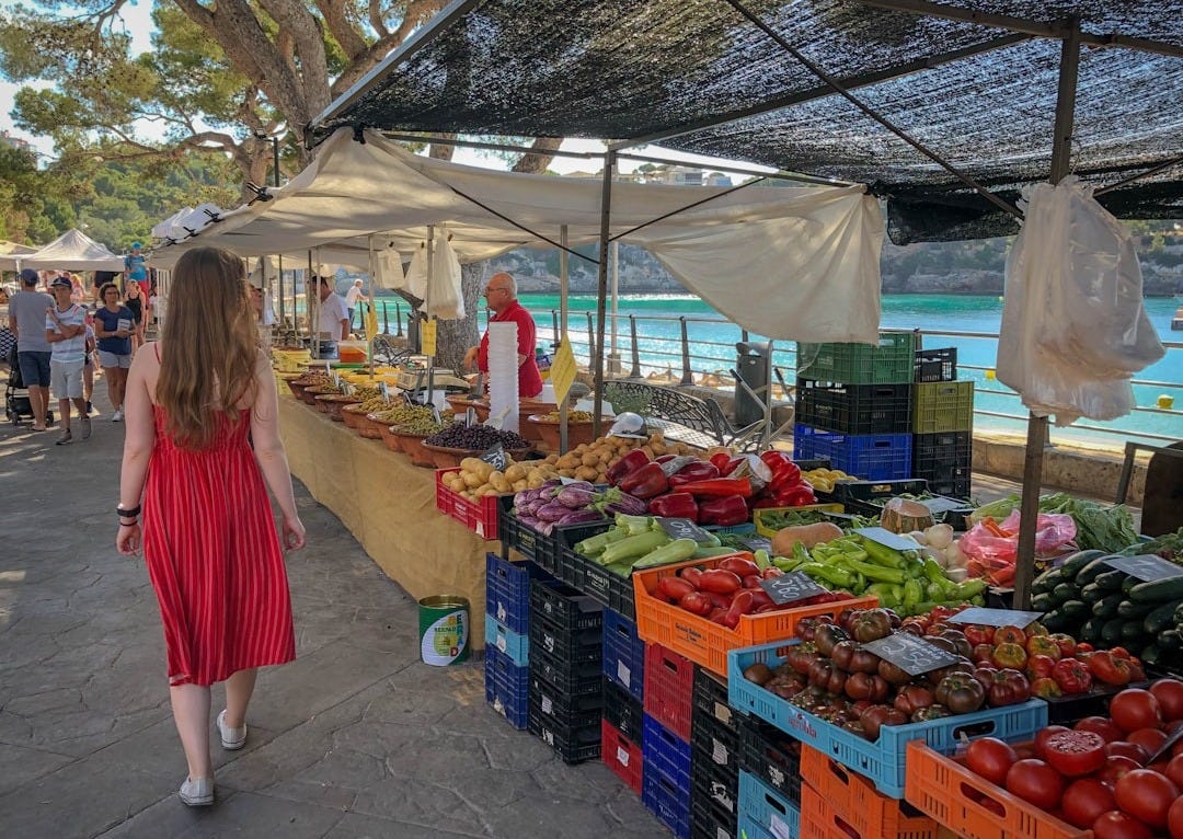 woman walking beside fruit and vegetable vendors