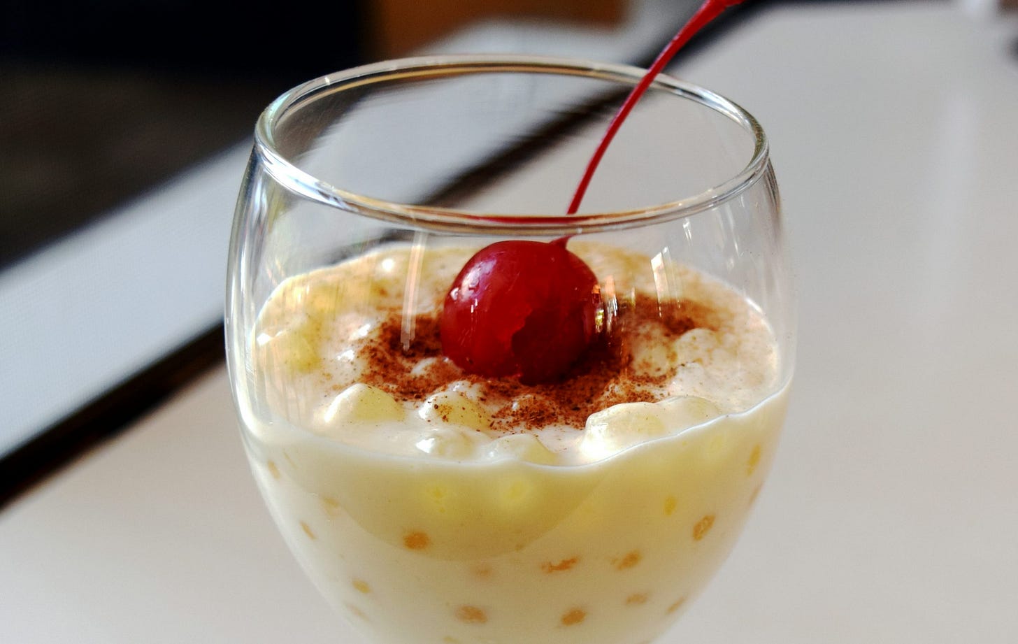 a dessert in a wine glass with a cherry on top