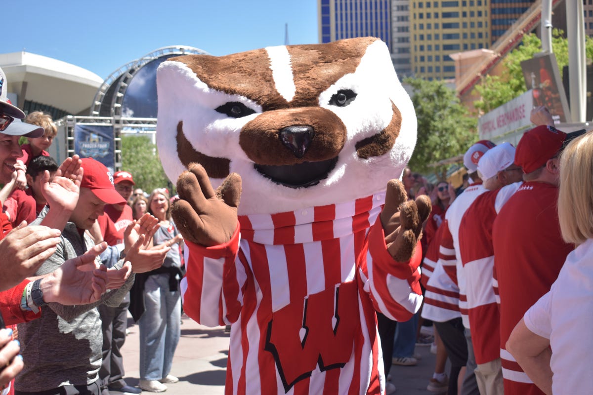 Wisconsin hockey mascot Bucky Badger claps his hands with fans nearby