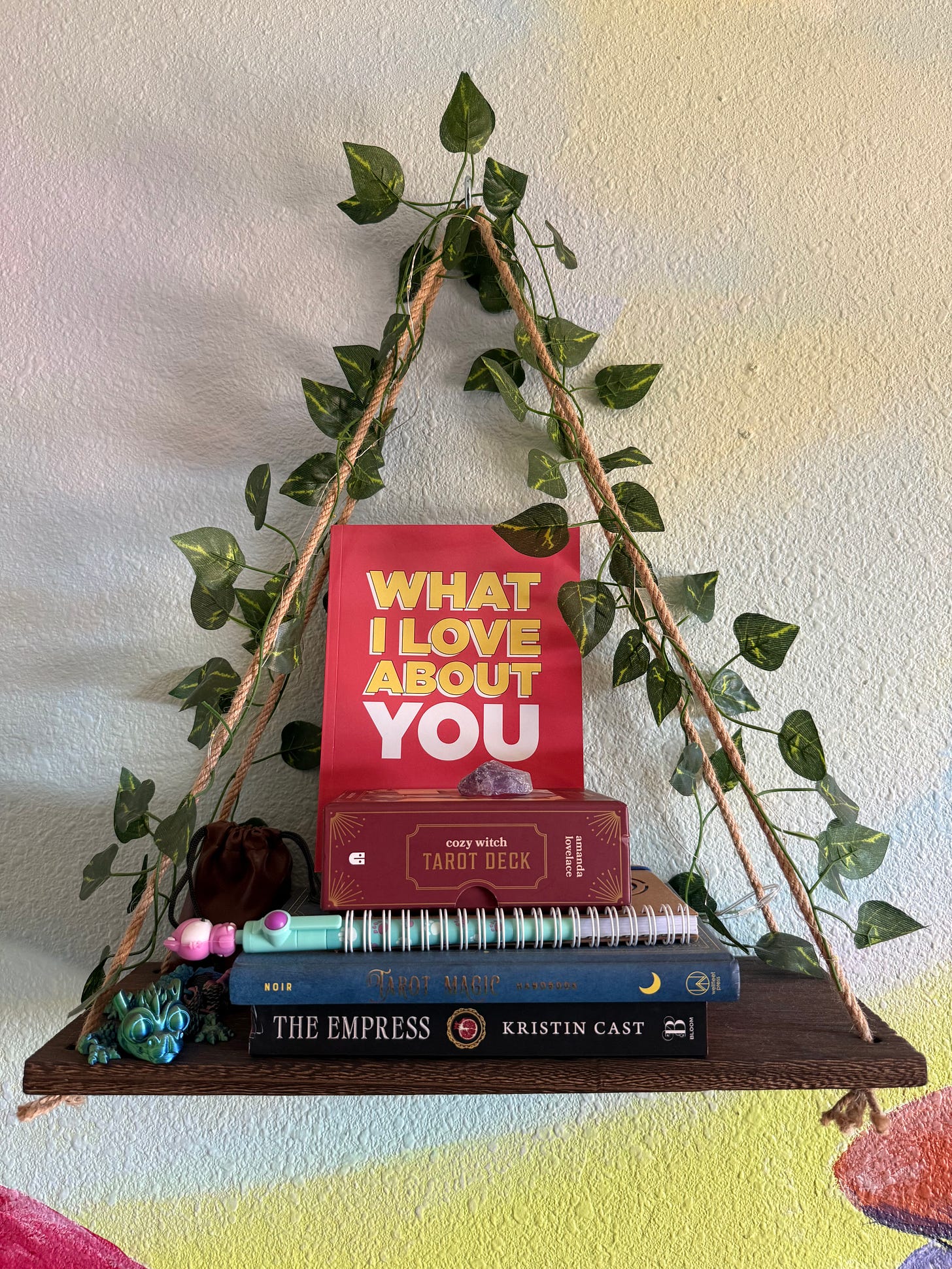 Cozy witch tarot deck on a wooden hanging shelf with green ivy vines Cozy witch tarot deck on a wooden hanging shelf with green ivy vines