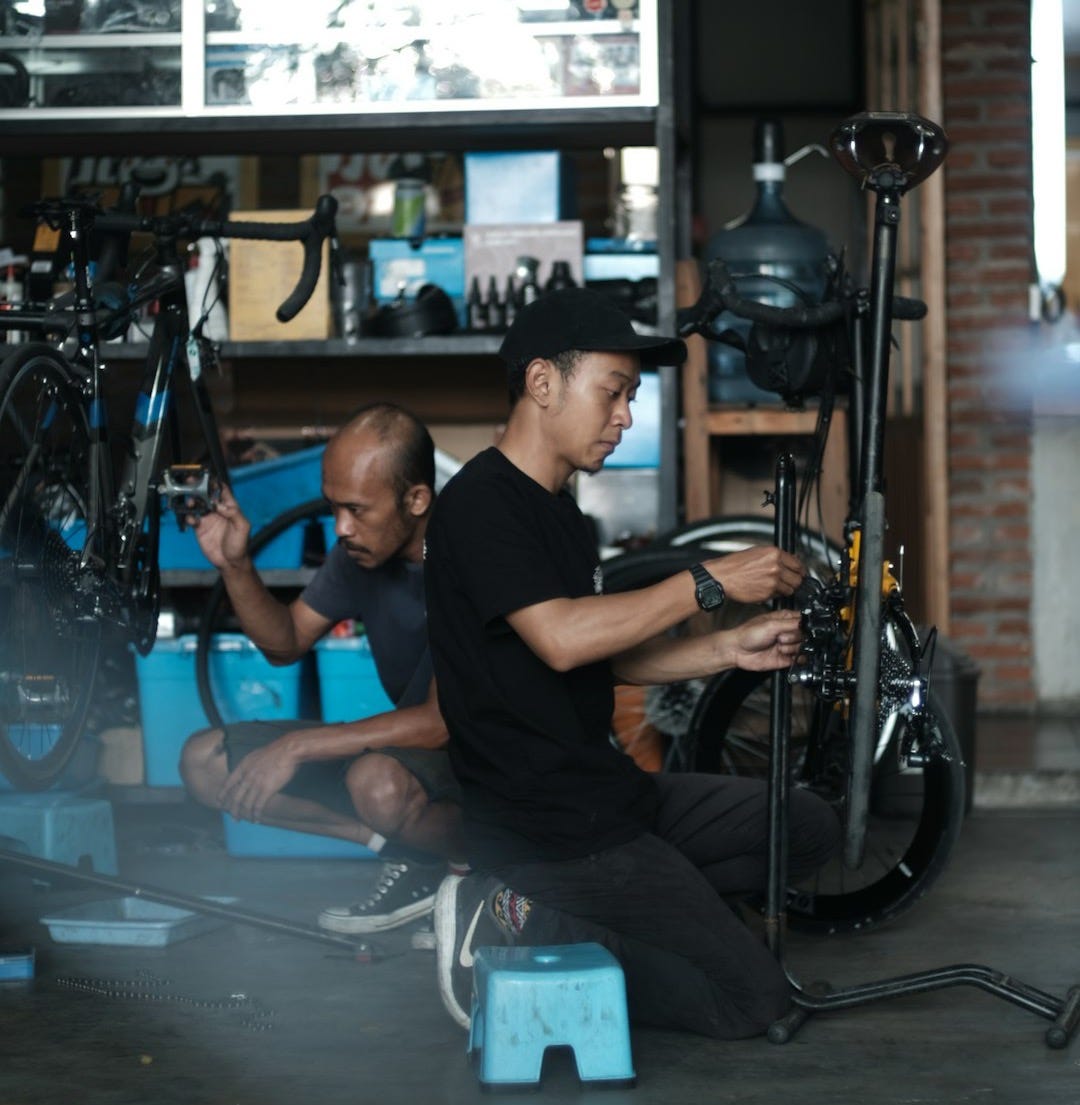 a couple of men sitting on a bench with a guitar and a drum set