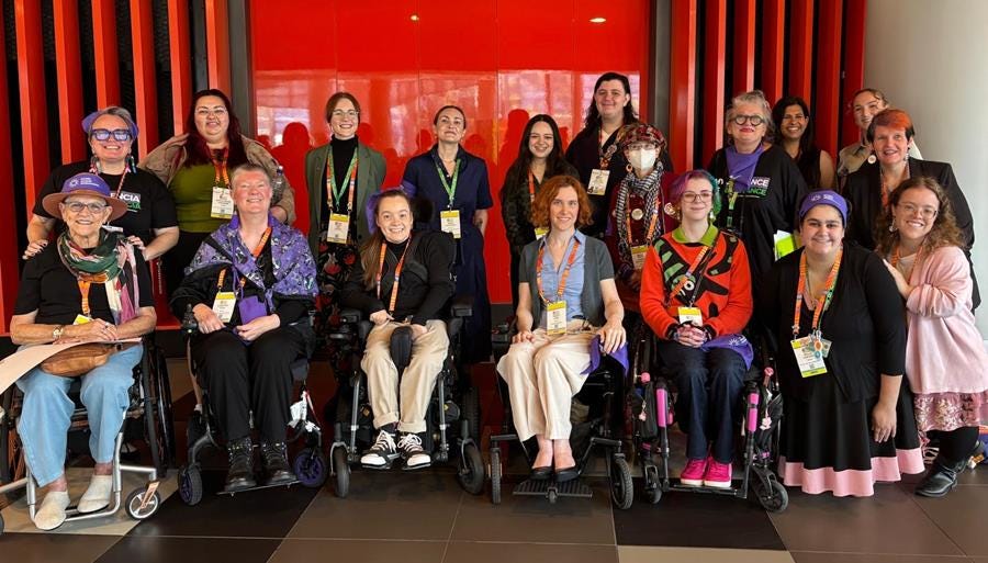 A group photo of about twenty disability advocates smiling together.