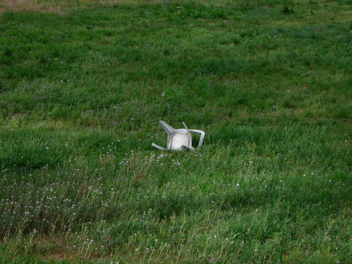 una silla de plástico rota en medio de un campo de hierba verde