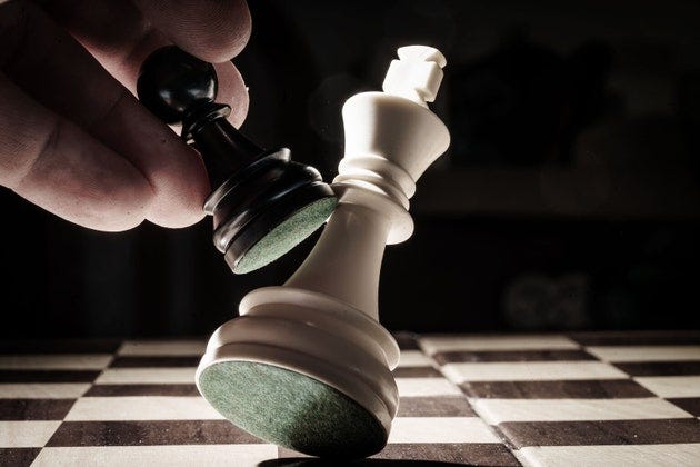 Black pawn knocking down white king on chessboard Black pawn knocking down white king on chessboard