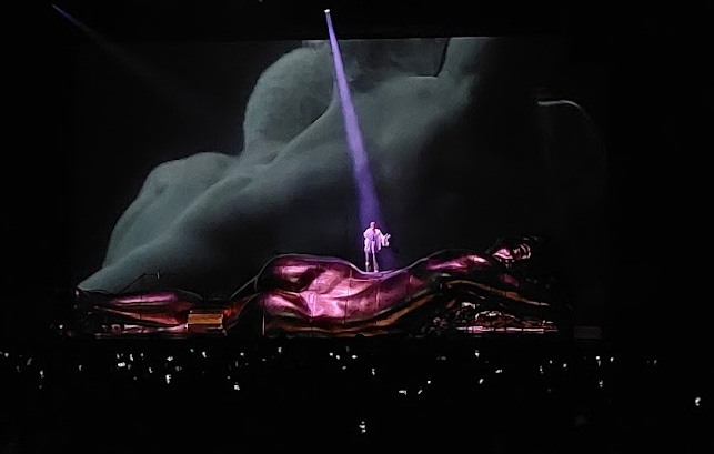 Sam Smith on stage with a beam of purple light shining on them 