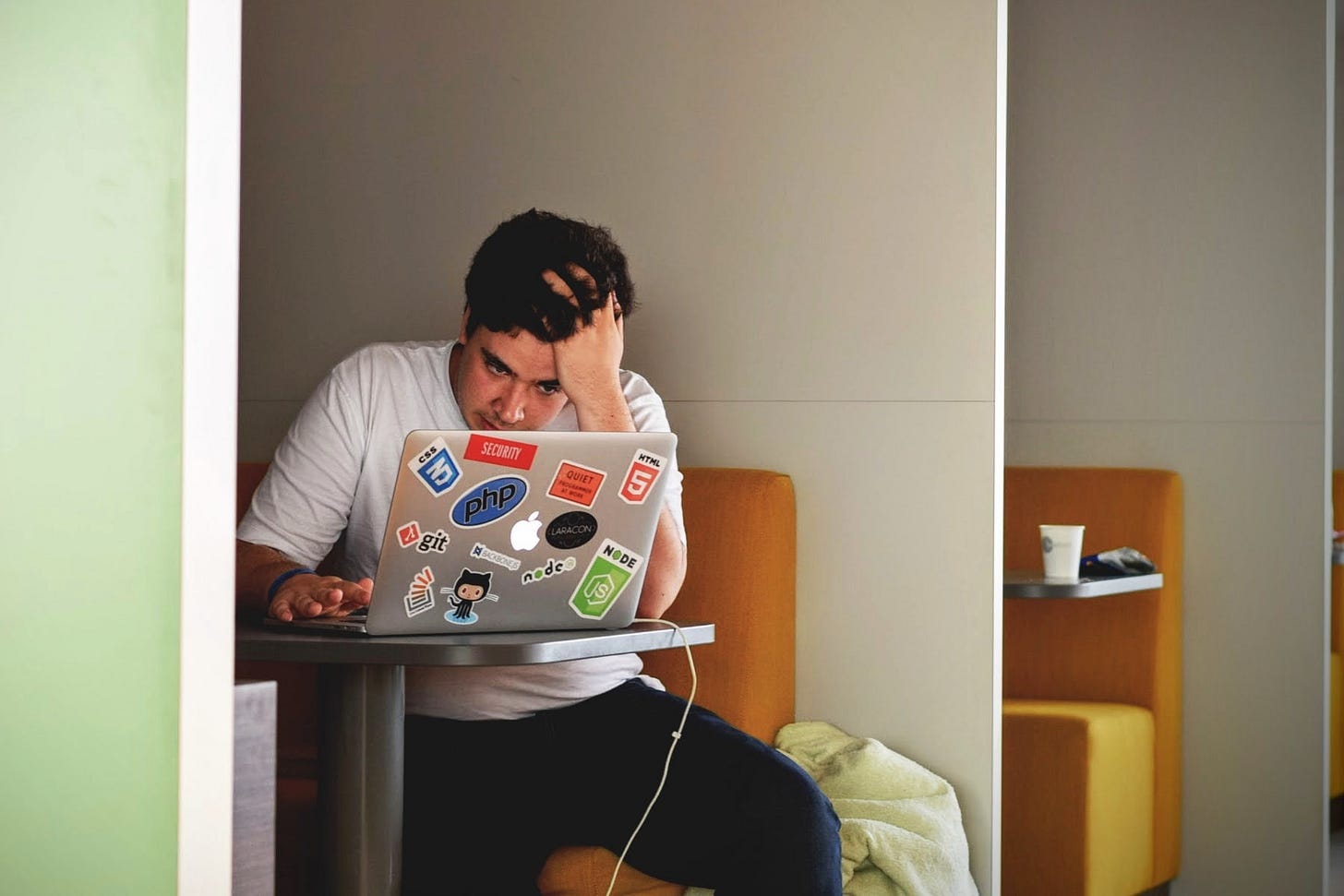 Frustrated-looking man sitting and looking at a laptop screen.