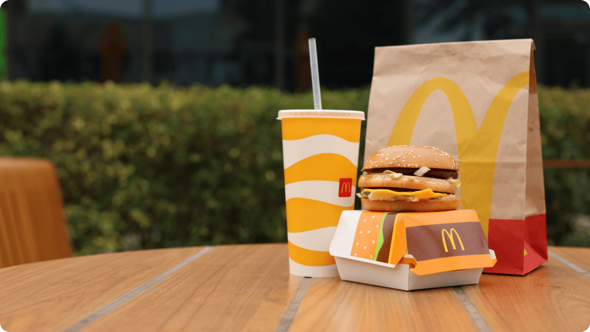 McDonald’s meal with burger, drink, and bag on outdoor table, symbolizing the company’s $200 million regenerative ranching pledge. McDonald’s meal with burger, drink, and bag on outdoor table, symbolizing the company’s $200 million regenerative ranching pledge.