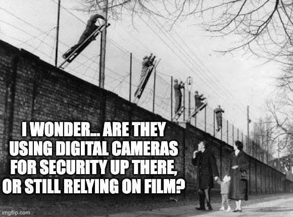 Black-and-white photo of people climbing over the Berlin Wall, edited with meme text: “I wonder… are they using digital cameras for security up there, or still relying on film?” A humorous investing meme referencing Kodak’s failure to adapt from film to digital, connecting to the theme of walls, moats, and the rise and fall of companies.
