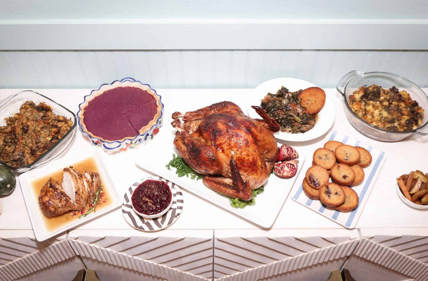 Southern Thanksgiving dinner spread Black chef style: featuring a golden roasted turkey, purple sweet potato pie, soul food collard greens, oyster dressing, bread pudding, candied yams, corn pudding casserole, and cranberry sauce — a complete holiday feast served family-style by soul food expert Shaunda Necole for The Soul Food Pot.