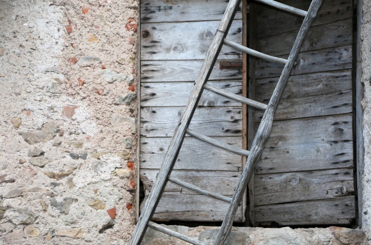 Old wooden ladder leaning to the right in front of old house