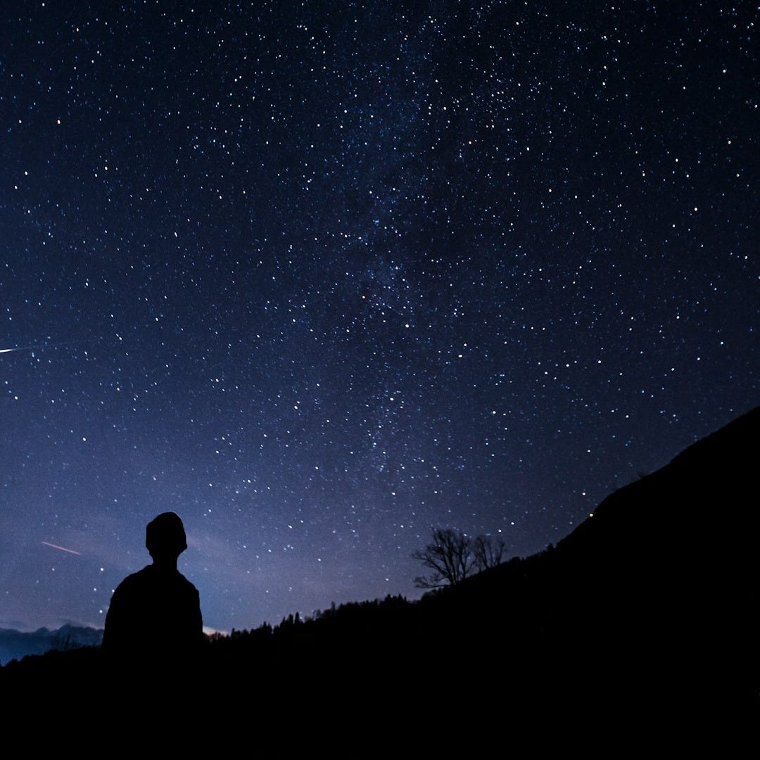 silhouette of man looking at milky way