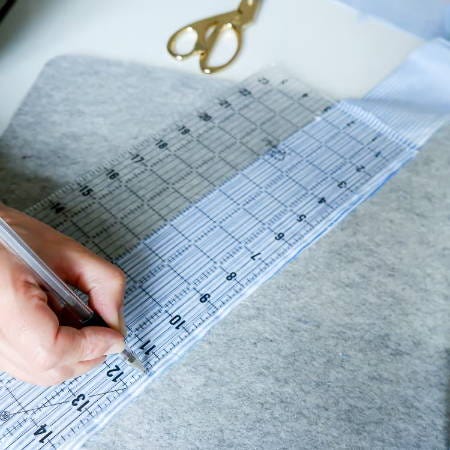 marking blue cotton fabric at 11 ½ inches with a marking pen and a ruler marking blue cotton fabric at 11 ½ inches with a marking pen and a ruler