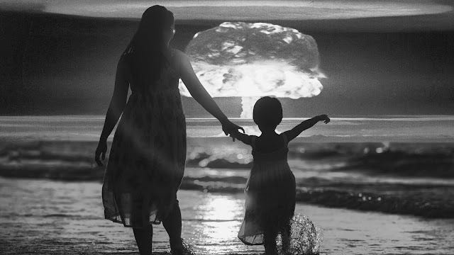A grayscale, high-contrast silhouette of a woman and child standing on a beach, watching a massive nuclear mushroom cloud erupting on the horizon.