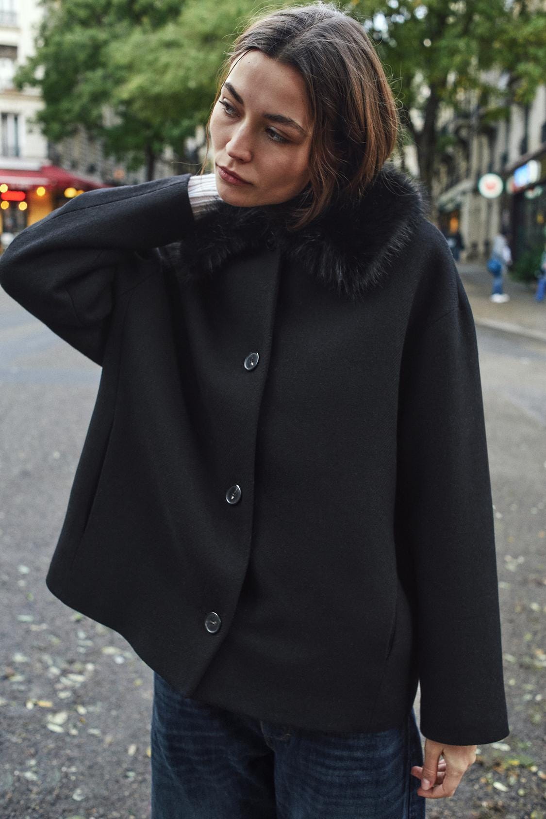 Black coat set with a fur collar and front buttons, paired with blue jeans.