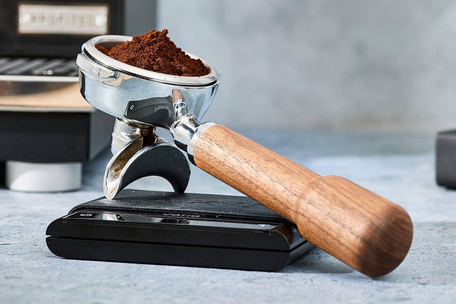A portafilter filled with freshly ground coffee resting on a digital scale, highlighting key tools for espresso preparation