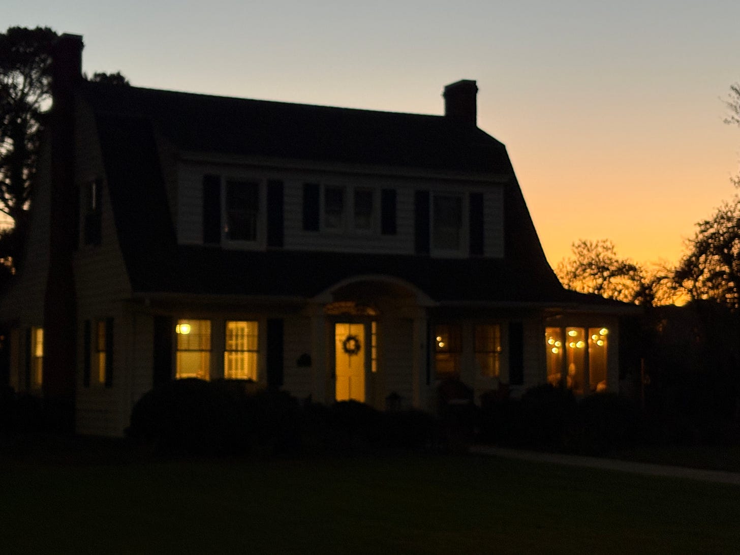 photo of house with warm light and sunset in background