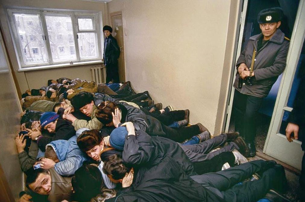 Detained bandits and suspected gangsters lie on the ground, awaiting interrogation in Yekaterinburg, Russia, 1992, amidst the post-Soviet era's turmoil.