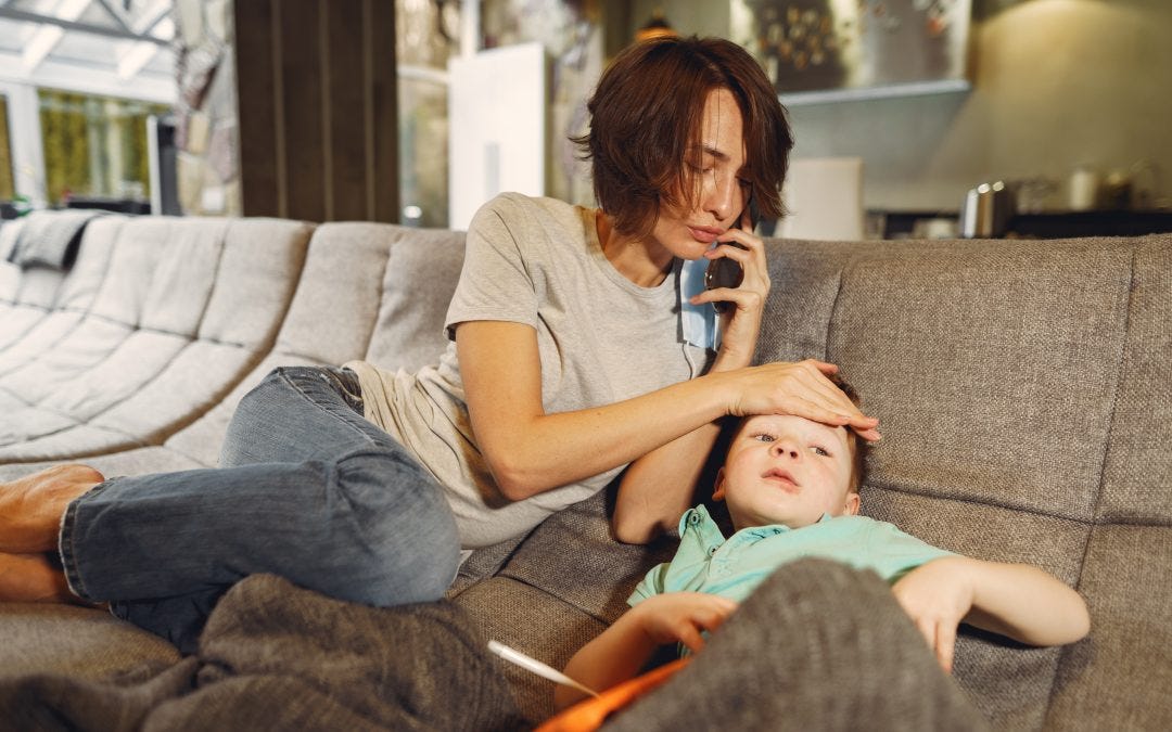 Mother and son sit on the couch. Mother has hand on son's head. Mother and son sit on the couch. Mother has hand on son's head.