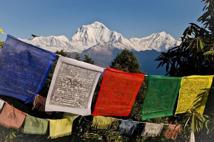 This may contain: there are many colorful flags hanging on the clothes line with mountains in the background and blue sky