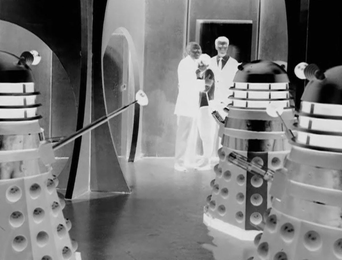 An image from production of The Daleks showing William Hartnell, Carole Ann Ford and William Russell, playing Dr Who, Susan and Ian Chesterton, respectively, confronted by three daleks in their metallic city on Skaro; the image is in negative An image from production of The Daleks showing William Hartnell, Carole Ann Ford and William Russell, playing Dr Who, Susan and Ian Chesterton, respectively, confronted by three daleks in their metallic city on Skaro; the image is in negative