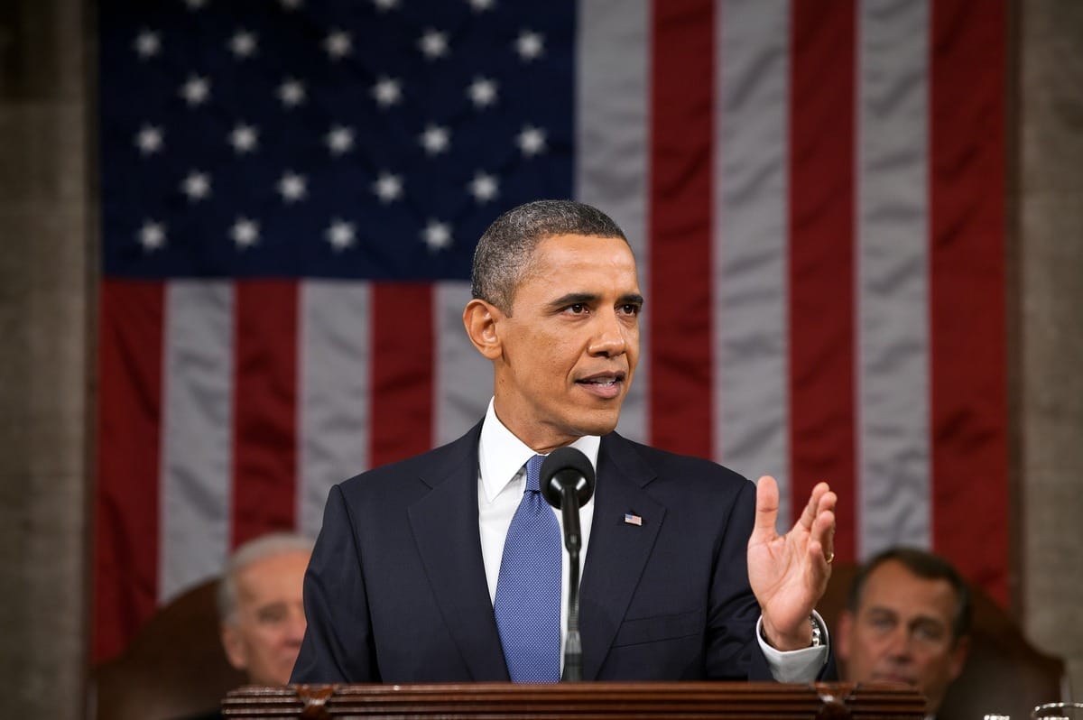 President Barack Obama delivers a speech from the podium in Congress, with then-Vice President Biden and then-Speaker of the House John Boehner sitting behind him.