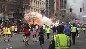 Runners continue to run towards the finish line as an explosion erupts at the finish line of the Boston Marathon Runners continue to run towards the finish line as an explosion erupts at the finish line of the Boston Marathon