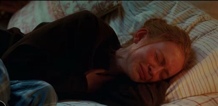 This may contain: a young man sleeping on top of a bed with his eyes closed and head turned to the side