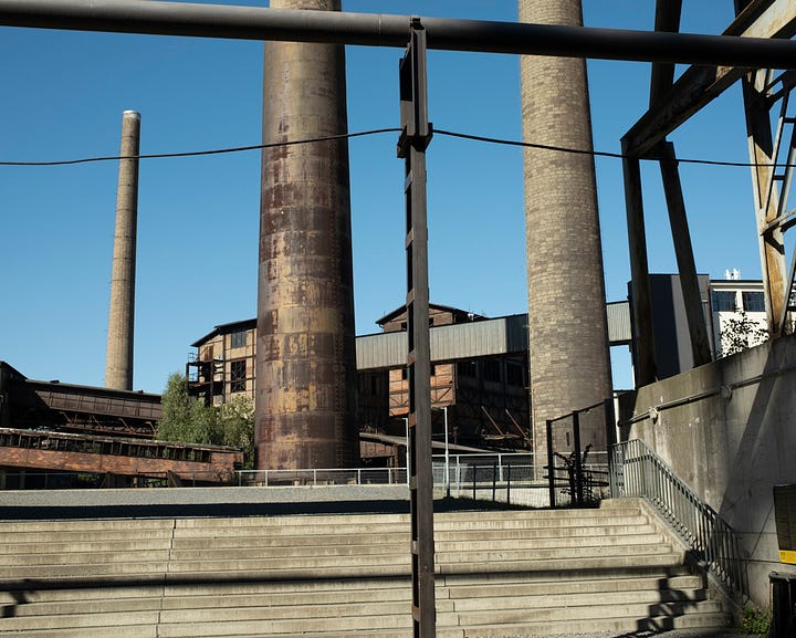 Colour photographs of decaying old steel factory; lots of rust pipes, stacks, and other industrial architecture