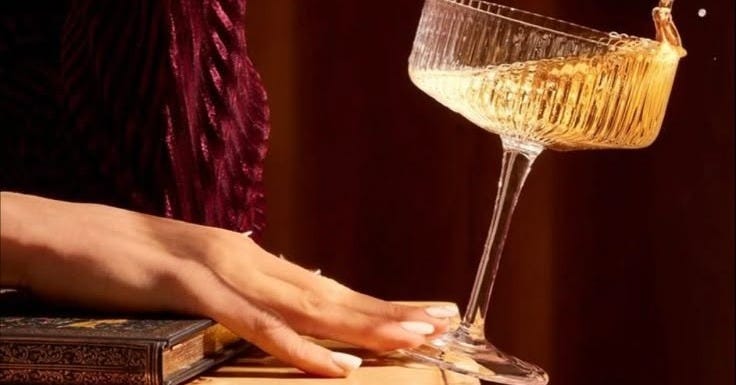 This may contain: a woman's hand holding a wine glass on top of a table This may contain: a woman's hand holding a wine glass on top of a table