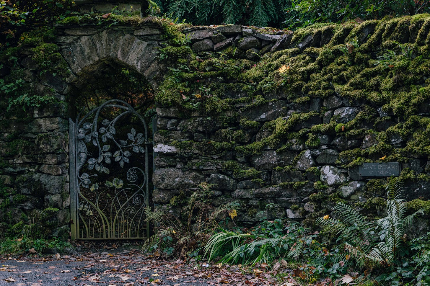 Moss-covered stone wall and ornate metal gate in the Lake District, England, historic countryside architecture. Moss-covered stone wall and ornate metal gate in the Lake District, England, historic countryside architecture.