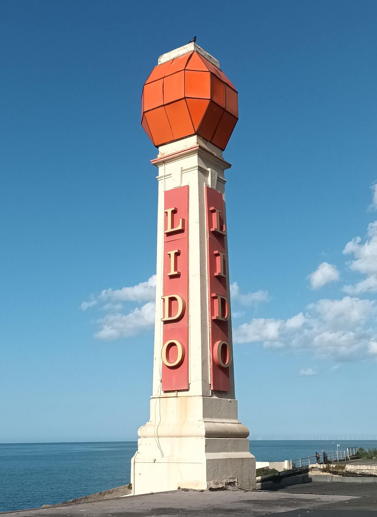 Margate lido sign, tall and thin, blue skies with white clouds behind