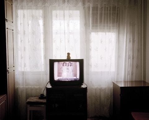 This may contain: an old television sitting on top of a table in front of a curtained window