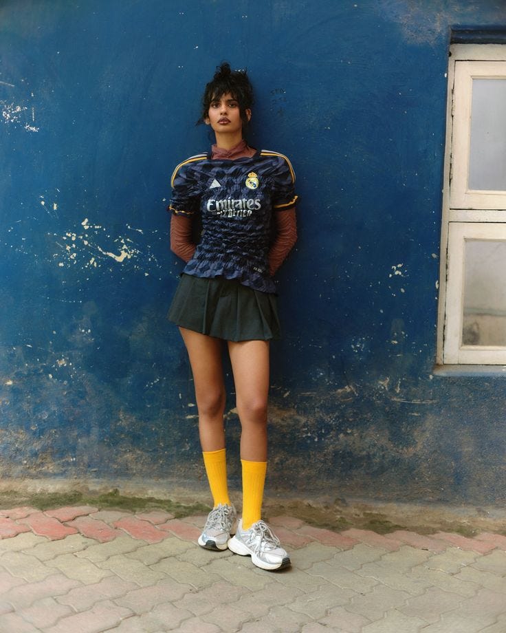This may contain: a woman standing in front of a blue wall with her hands on her hips wearing yellow socks