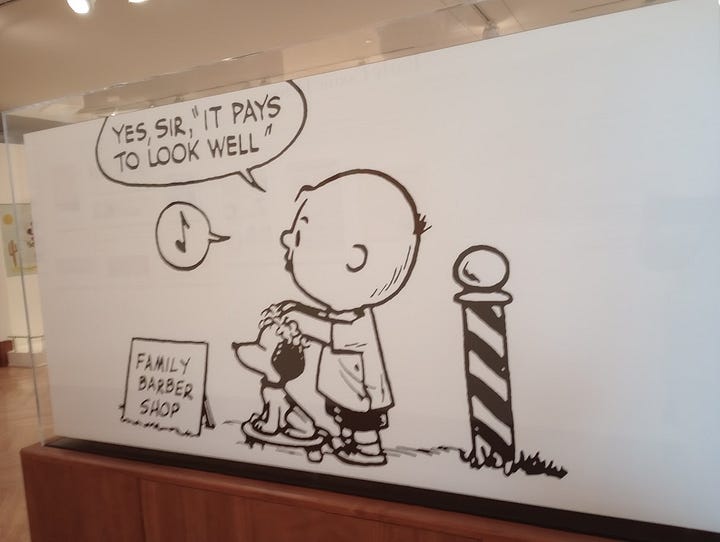 Newspaper ad for Charles F. Schulz's barbershop, and cartoon of Charlie Brown with barber pole and sign saying Family Barber Shop