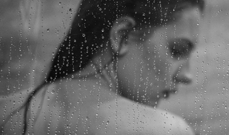 a black and white photo of a woman in the rain