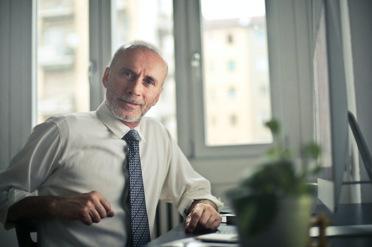 older man sitting at desk in office