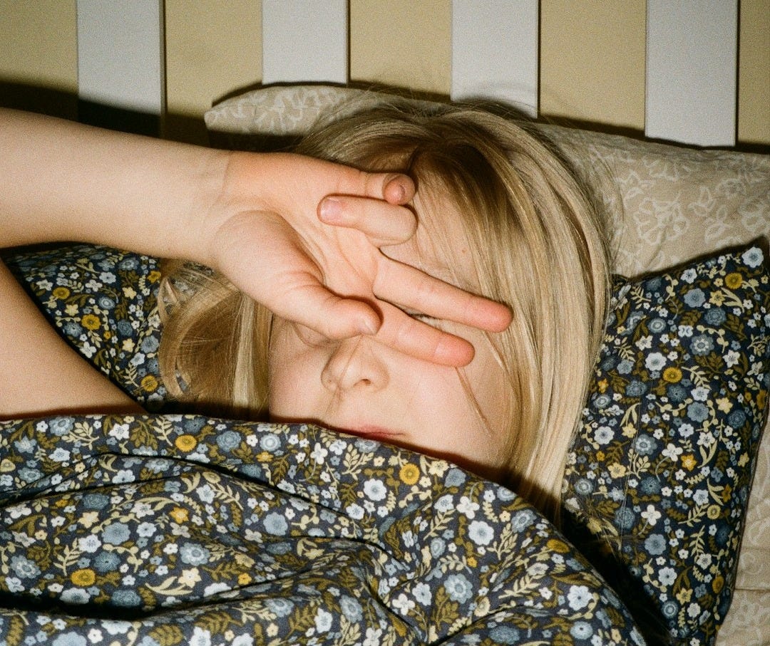 A woman laying in bed with her hand on her head A woman laying in bed with her hand on her head