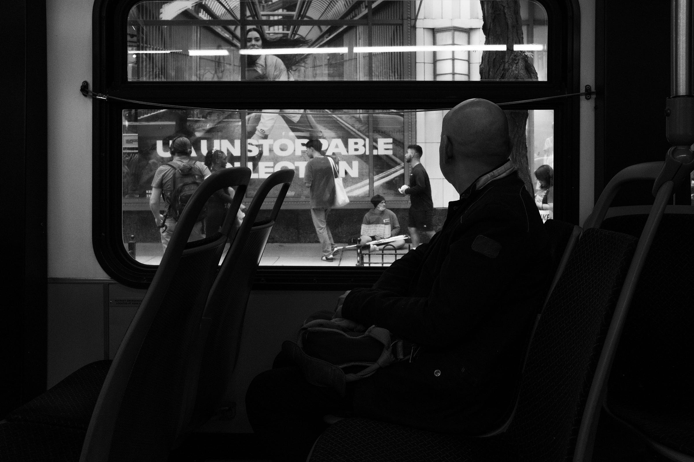 A black and white photo of a person looking out the window on the "L" reading the word Unstoppable.