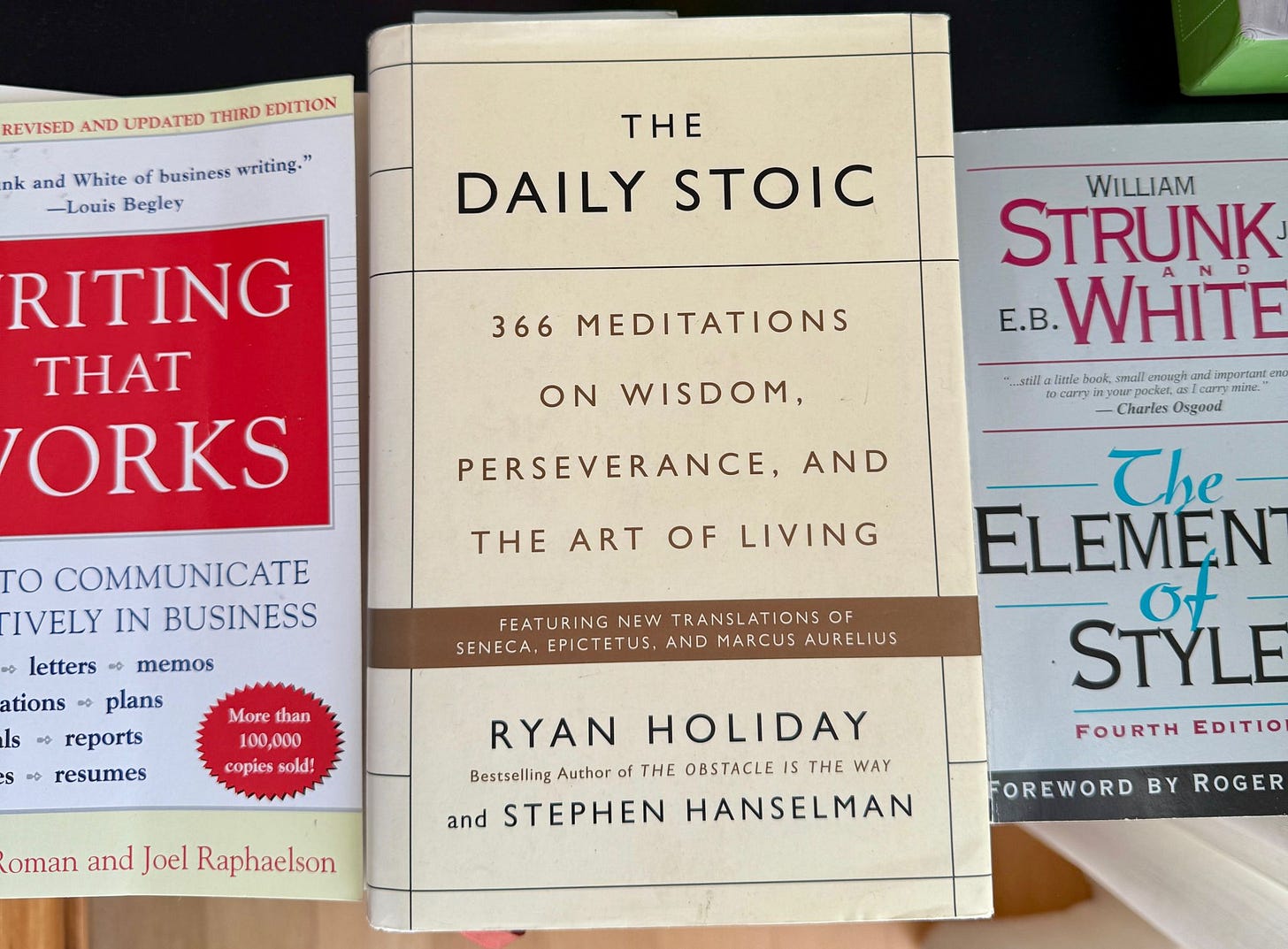 Livros Writing That Works, The Daily Stoic e The Elements of Style sobre uma mesa. Guias sobre escrita eficaz, filosofia estoica e estilo literário, fundamentais para profissionais que buscam clareza, persuasão e propósito.