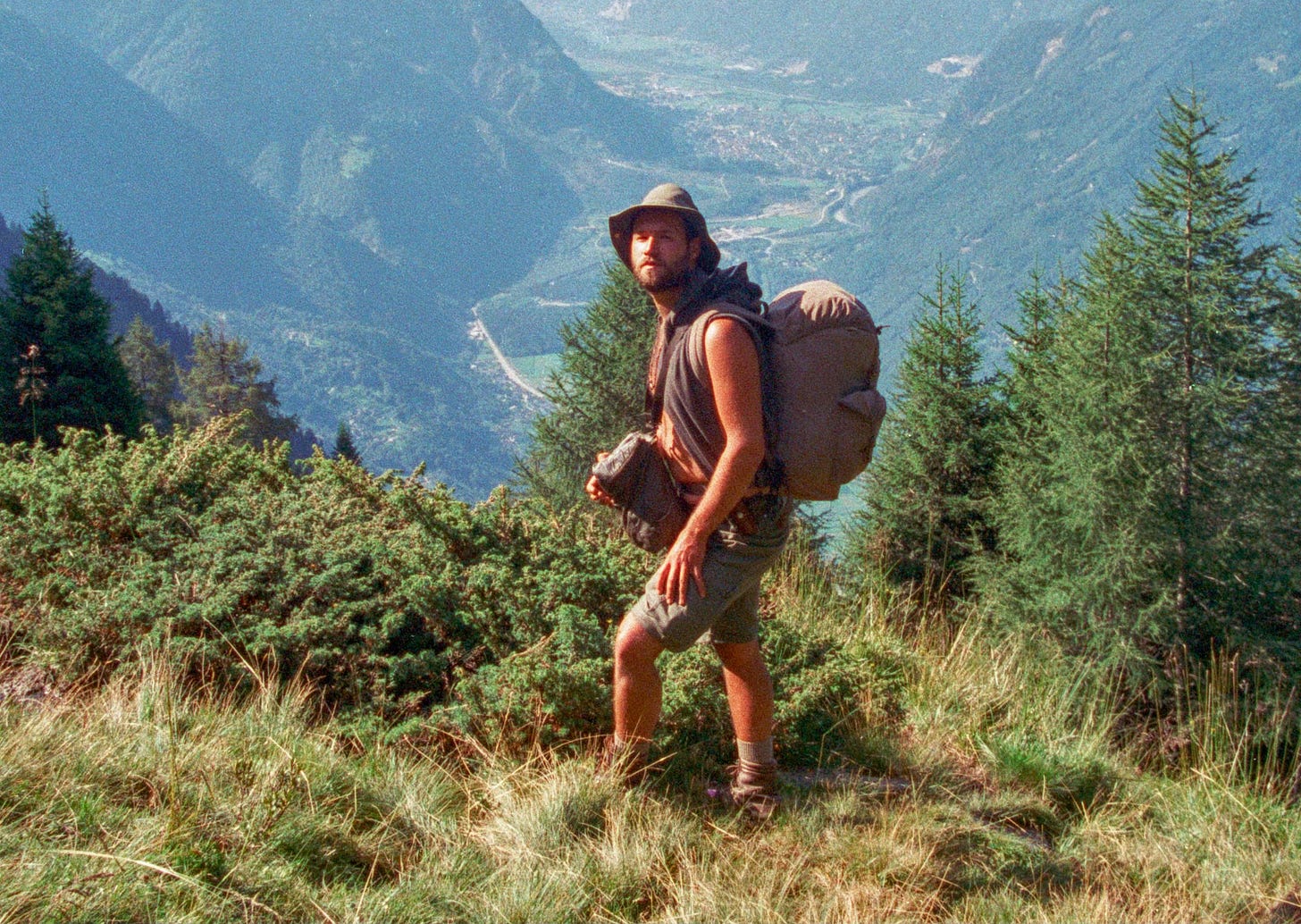 Me 25 years ago wearing a Tilly hat, vest, shorts and a couple of bags front and back. I'm stood high in a Swiss valley.