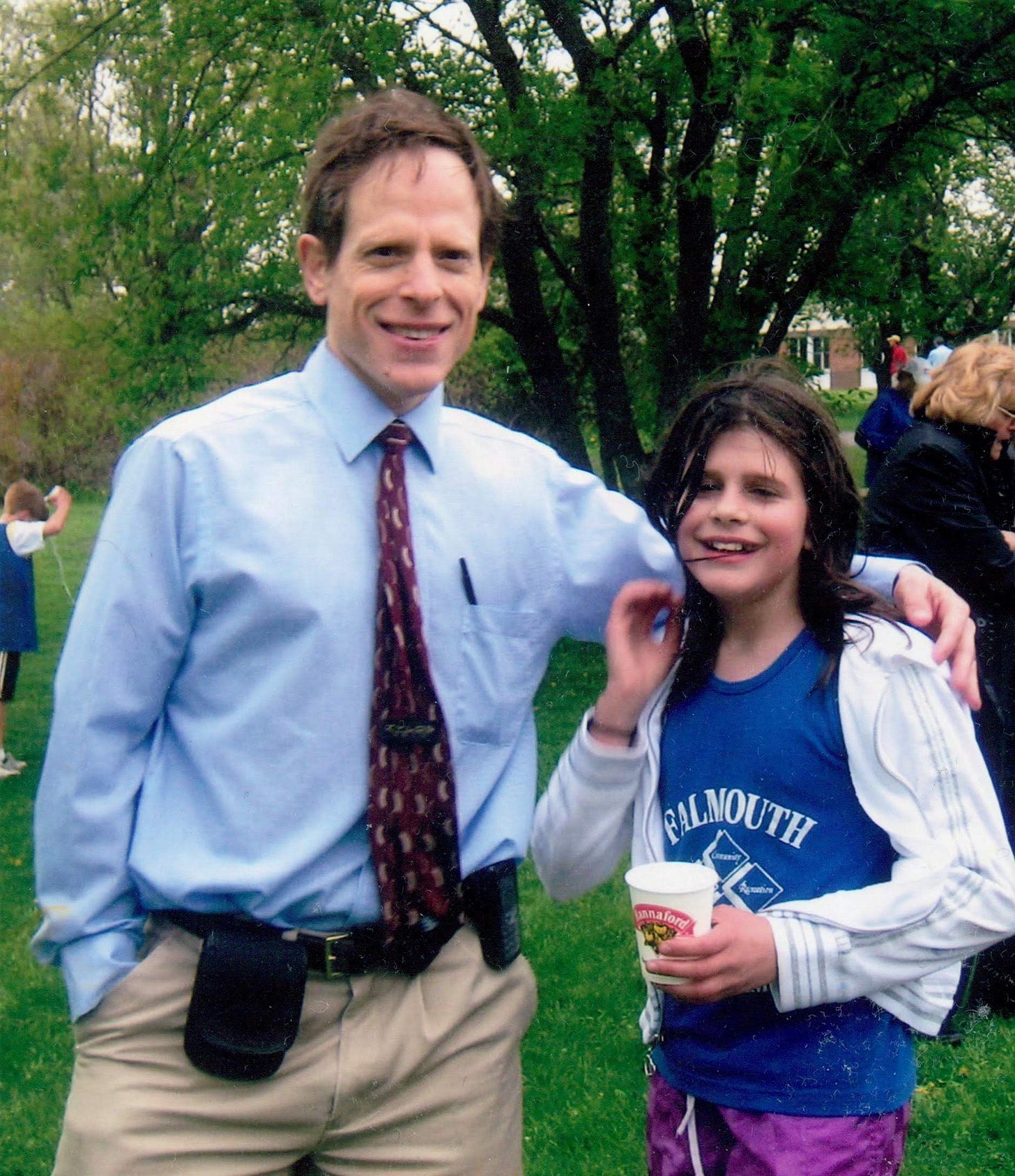 A man stands with his arm around a 10 year old girl with messy hair