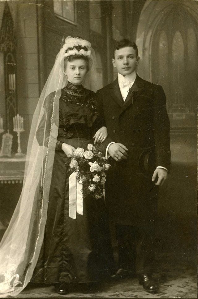 This may contain: an old black and white photo of a man and woman in wedding attire standing next to each other