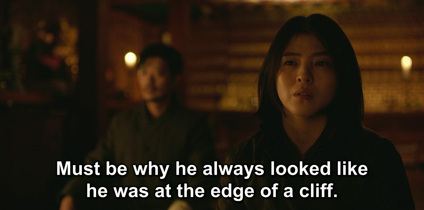Yoon Ji-woo with Choi Mu-jin the background at the temple, episode six of My Name (2021) with the line "Must be why he always looked like he was at the edge of a cliff.”